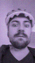 a selfie of a white person, wearing either headphones or a helmet, making an odd expression. the photo is edited to be colorized into a monochrome purple-ish color palette.